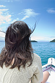女人坐在船上，望着大海，刮风