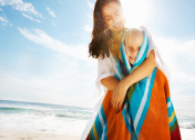 在海滩上，母亲用毛巾盖住女儿