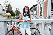 一名夏威夷女子骑着自行车在市中心使用智能手机