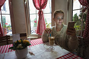 年轻女子在咖啡厅喝咖啡时使用手机。