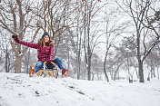 年轻女子滑着雪橇下山