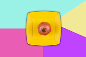黄色塑料盘上的石榴，背景是彩色的。