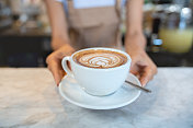 特写上的一个女服务员服务的一杯咖啡在咖啡馆