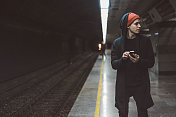 年轻的滑冰男子在火车站使用手机