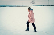 一个年轻女子在一个下雪天走在大自然中