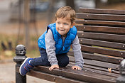 爬上公园长椅的男孩微笑着