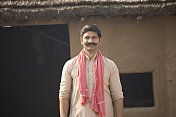 一个印度农民站在村舍前