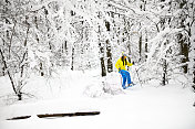 一个爱冒险的女人用她的雪鞋和手杖在冰冻的森林的深雪中跋涉