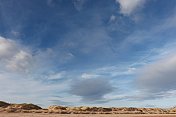 蓝天下的沙丘和蓬松的白云