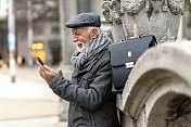 在城市街道上拿着手机的成熟商人