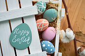直接在上面观看彩色的彩蛋与点和条纹放置在与干草的木箱，在贺卡上的复活节快乐字母