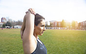 年轻女性健身训练前在公园。健康的年轻女子在户外热身她伸开双臂，看向别处