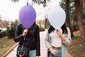 两个傻乎乎的女性朋友把气球举在头上