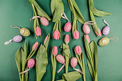 复活节彩蛋和粉红色的郁金香花在绿色的背景