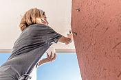 用油漆刷画阳台天花板的女人的低角度视图