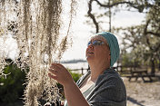 在北佛罗里达的Ochlockonee河州立公园，成熟的有吸引力的白种女人正在探索附生植物Tillandsia usneoides。