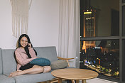 亚洲华人女性在家里用手机独自微笑