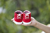 一幅孕妇抱着一双红色运动鞋婴儿鞋的肖像