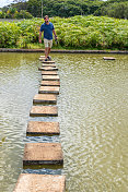 一名巴西男子踩着垫脚石穿过池塘