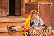 穿着传统服装坐在伊朗古老村庄Abyaneh街道上的皱巴巴的老妇人
