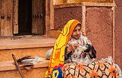 穿着传统服装坐在伊朗古老村庄Abyaneh街道上的皱巴巴的老妇人