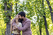 一对年轻夫妇正在公园里享受春天。他们在一起的时候，爱得更深。年轻的情侣在公园里微笑着拥抱。