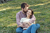 一对年轻夫妇正在公园里享受春天。他们在一起的时候，爱得更深。年轻的情侣在公园里微笑着拥抱。