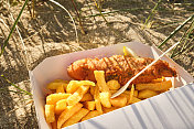 6月一个阳光明媚的晚上，康沃尔纽基菲斯特拉海滩的一盒炸鱼薯条。