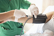 一名护士在诊所测量年轻女性病人的血压