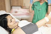 一名护士在诊所测量年轻女性病人的血压
