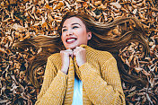 微笑的女人躺在秋叶上