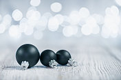 白色木材上的黑色圣诞装饰物和散焦圣诞灯