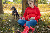 孕妇喜欢在公园里遛狗。