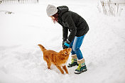 一个女人在雪中和狗玩