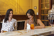 阿根廷布宜诺斯艾利斯市，两个美丽的年轻女人坐在酒吧里，微笑着聊天。