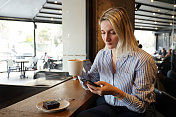 女商人使用智能手机，在咖啡馆喝咖啡