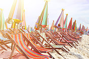 阳光灿烂的天空下，海边的沙滩伞和日光浴椅