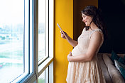 孕妇在窗前看平板电脑