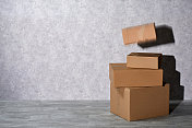灰色背景上一堆棕色的纸板箱，一个盒子飞着