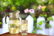 新鲜的柠檬水放在绿色的花园桌上