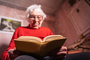 祖母戴着眼镜看书。