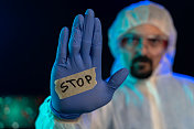 戴着防护眼镜和外科手套的科学家显示“停止”标志
