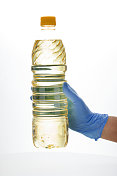 手握橡胶protect?ve手套，塑料油瓶与黄色盖