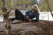 成熟的女人在河边的原木上放松