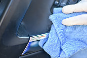 戴防护手套的妇女用洗手液清洗车门把手