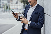 蓝色西装的成功商人正在街上用智能手机看东西