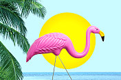 装饰的粉红色火烈鸟在太阳棕榈树和海洋前
