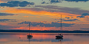 黄昏时湖面上船只的剪影和壮丽的云景