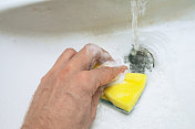 男手用黄色海绵清洗水槽孔