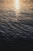 日落时平静水面上的涟漪、波浪和干扰